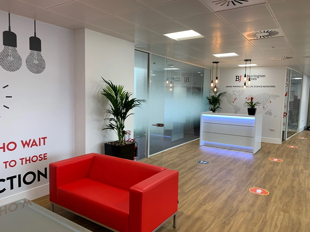 Office refurb | Office space with red sofa, plantlife and a modern reception with blue accent lights