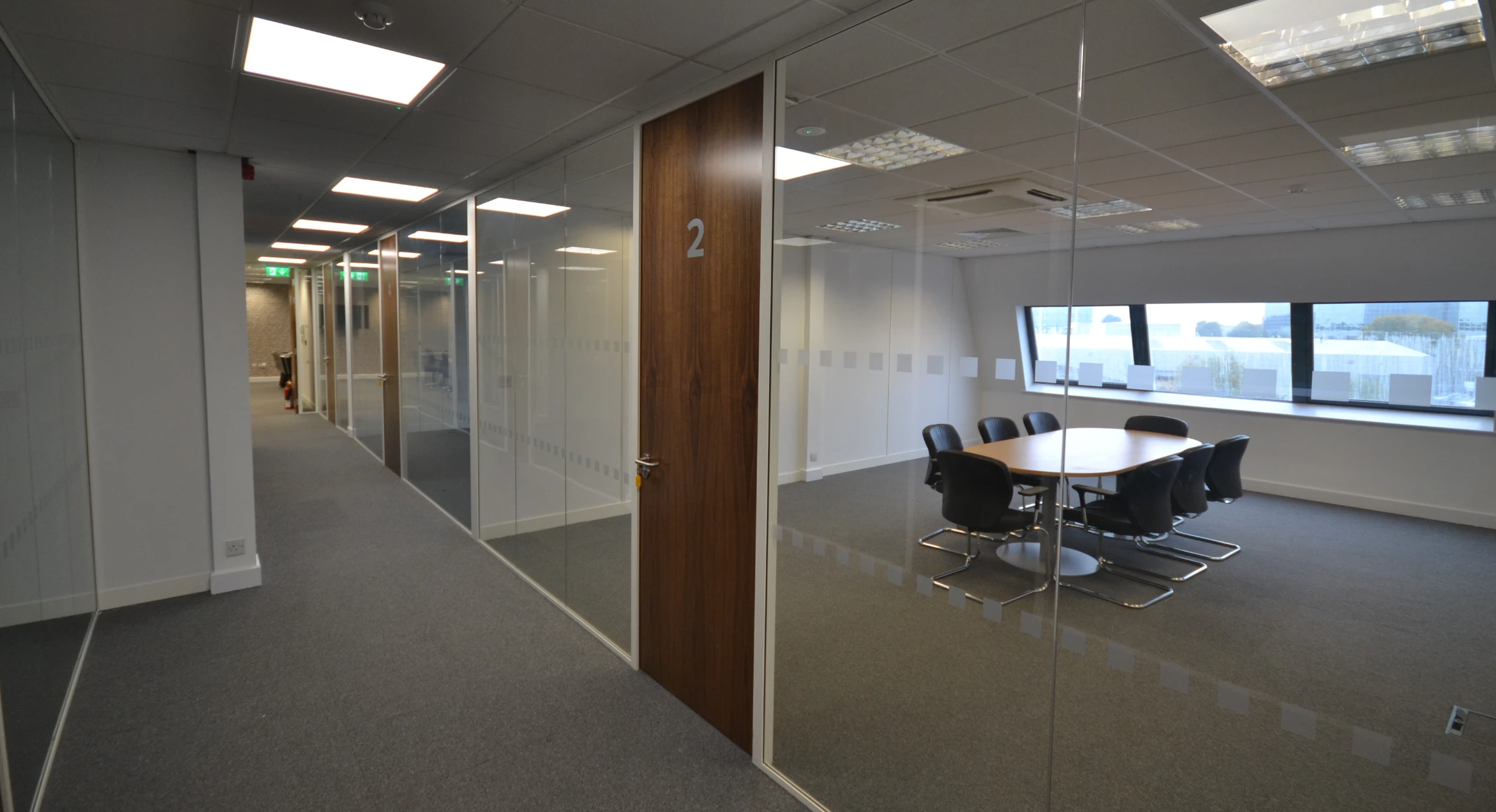 Commercial partition walls | glass partitions in hallway with wooden table at the end. Pot and plant on the table.