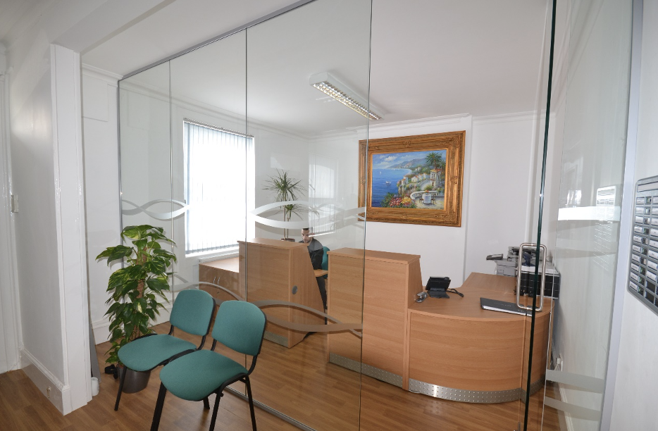 Framless glass office partitions | Office partitions in an office reception space with wood panelling.