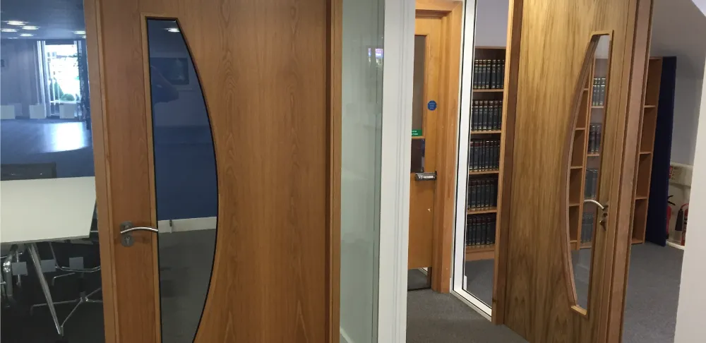 PDT Solicitors | Office space with glass partitions and wooden doors.